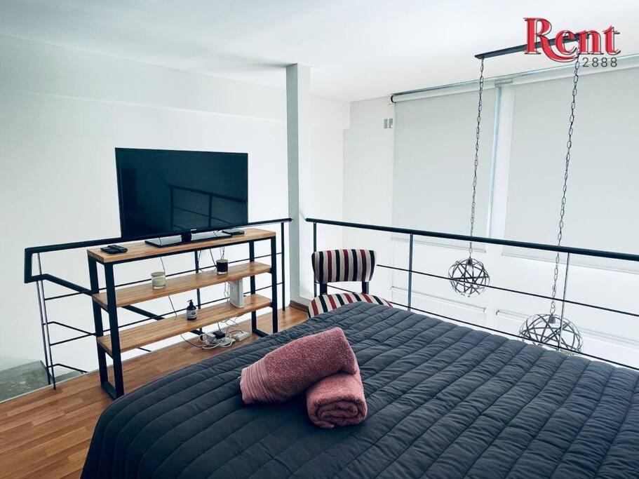 1 dormitorio con 1 cama, TV y silla en Rent Estomba en Buenos Aires