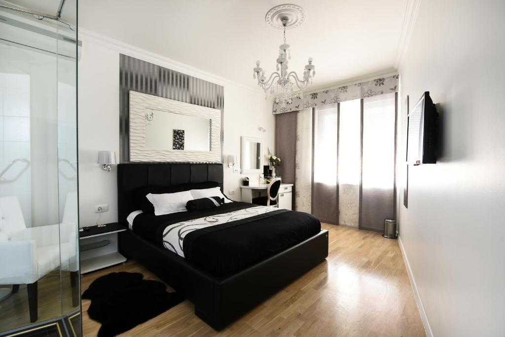 a bedroom with a black bed and a chandelier at Adriaticum Luxury Accommodation in Zadar