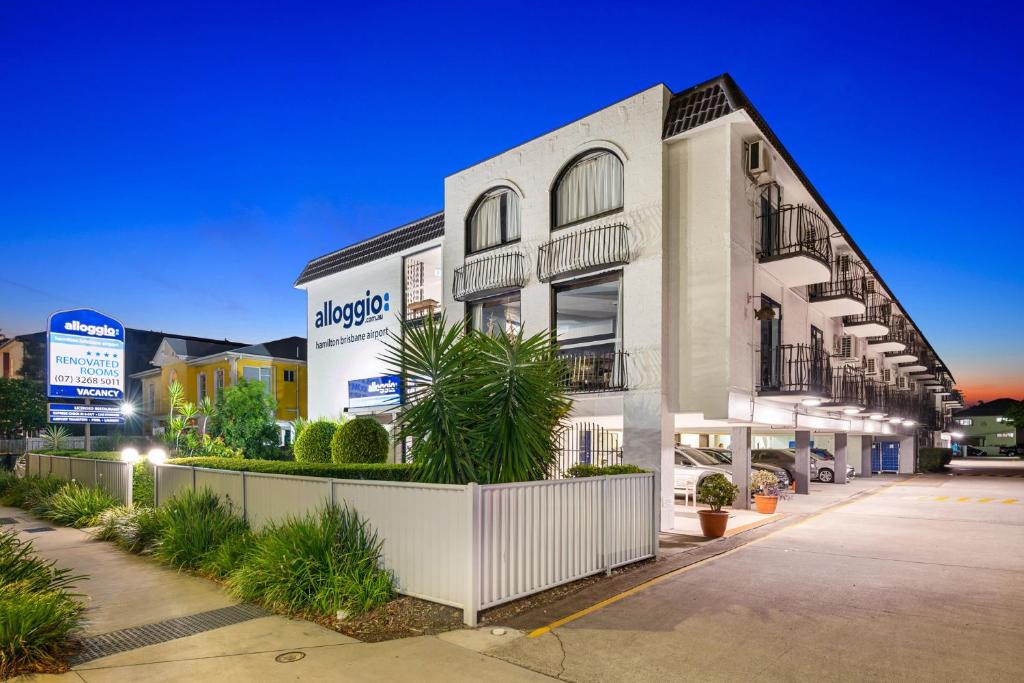 - un grand bâtiment blanc avec un panneau devant dans l'établissement Alloggio Hamilton Brisbane Airport, à Brisbane