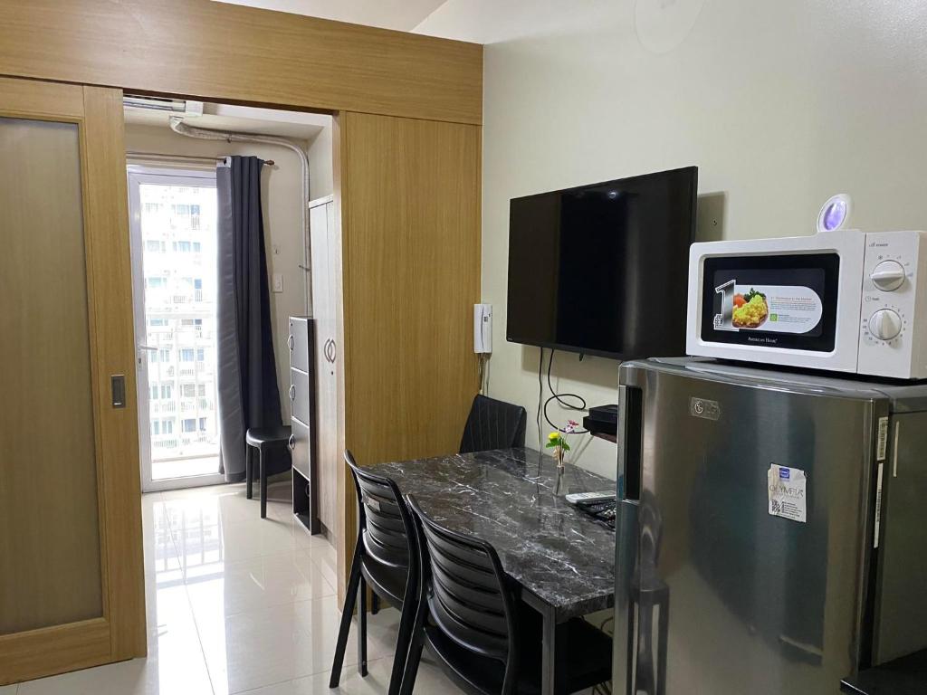 a room with a table and a microwave on a refrigerator at Shell Residences C15 Shortwalk Sm Mall Of Asia/Airport in Manila