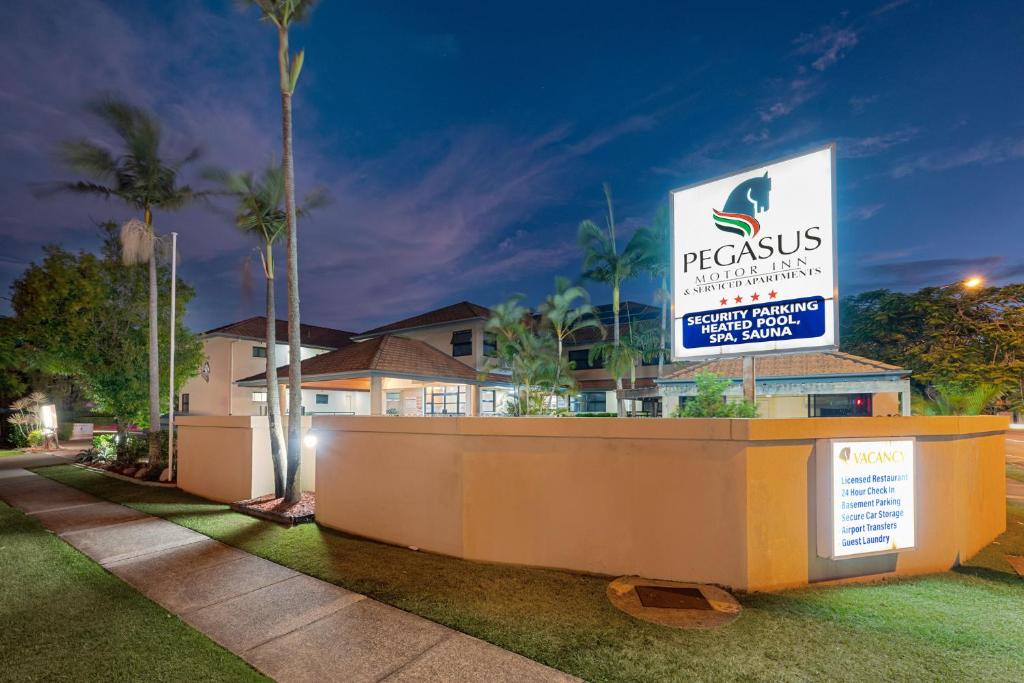 a sign in front of a house with palm trees at Pegasus Motor Inn and Serviced Apartments in Brisbane