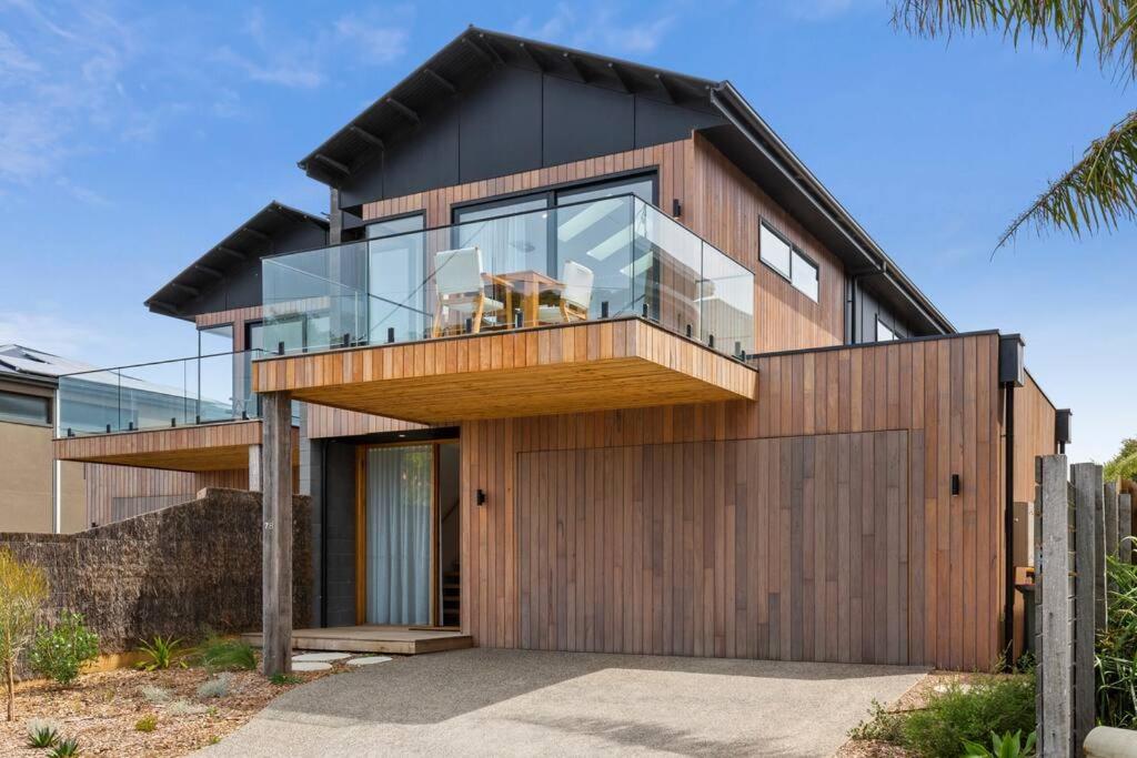 una casa con un balcón de cristal encima en Riverside Luxe- Brand New, 50m to river, 3 bedroom, pizza oven!, en Ocean Grove
