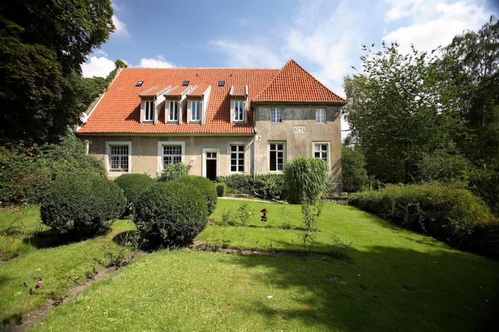 una casa con techo naranja en un patio verde en Haus Keppelborg: ZI Ferdinand mit Rosengartenblick, en Heek