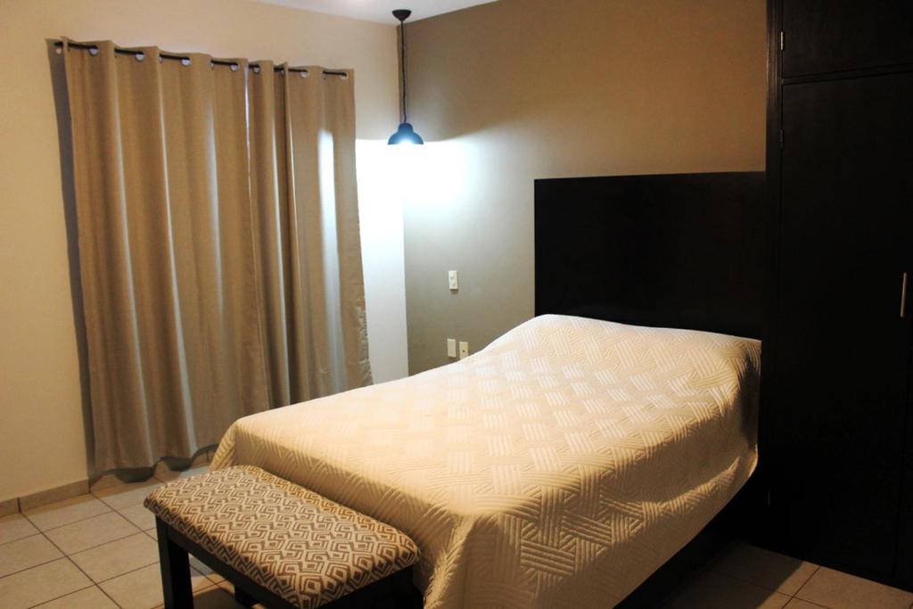 - une chambre avec un lit, une chaise et une lampe dans l'établissement Hotel Magnolia, à Tampico