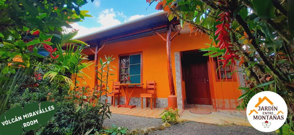 uma casa cor-de-laranja com um cartaz à frente. em Jardin entre Montañas em Bijagua