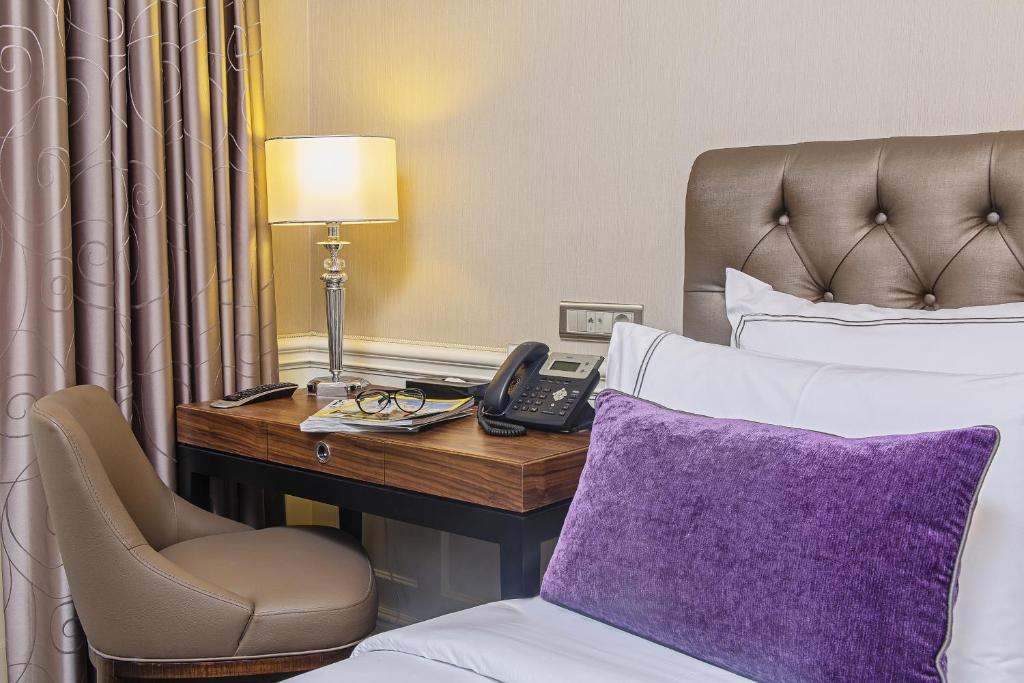 イスタンブールにあるMeroddi Bagdatliyan Hotelのベッド、デスク、電話が備わるホテルルームです。