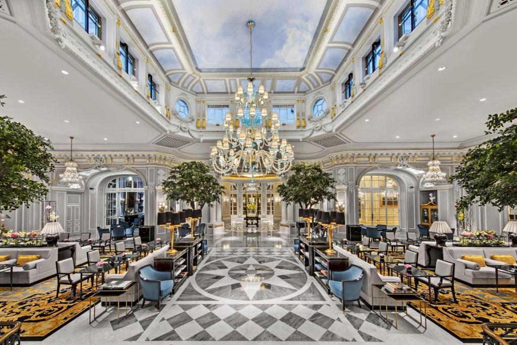 a lobby with a chandelier and tables and chairs at The St. Regis Rome in Rome