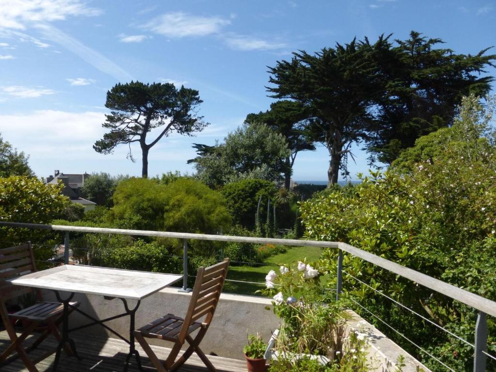 balkon ze stołem, krzesłami i drzewami w obiekcie Holiday flat with sea and garden view, just 400m from the beach in Port-Blanc w mieście Penvénan