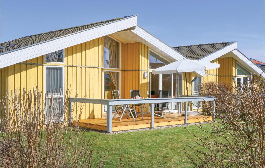 a yellow house with a deck and an umbrella at 2 Bedroom Nice Home In Rechlin in Rechlin