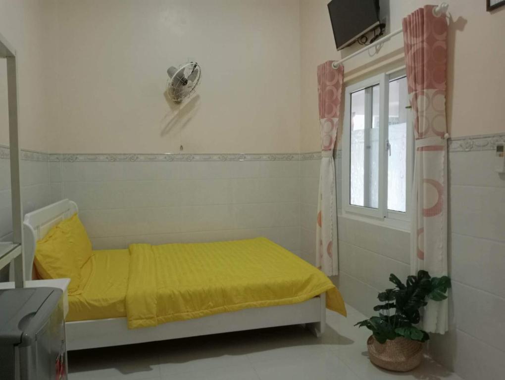 a small bedroom with a yellow bed and a window at Homestay 195/4 in Ấp Khánh Phước (1)