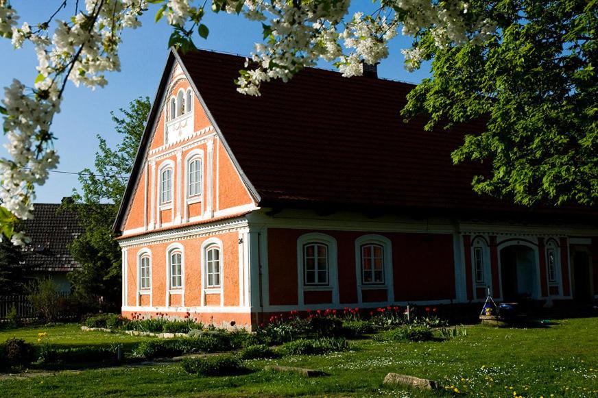 ein rotes Haus mit braunem Dach auf einem grünen Hof in der Unterkunft Růžová chalupa u Šimánků in Rtyně v Podkrkonoší