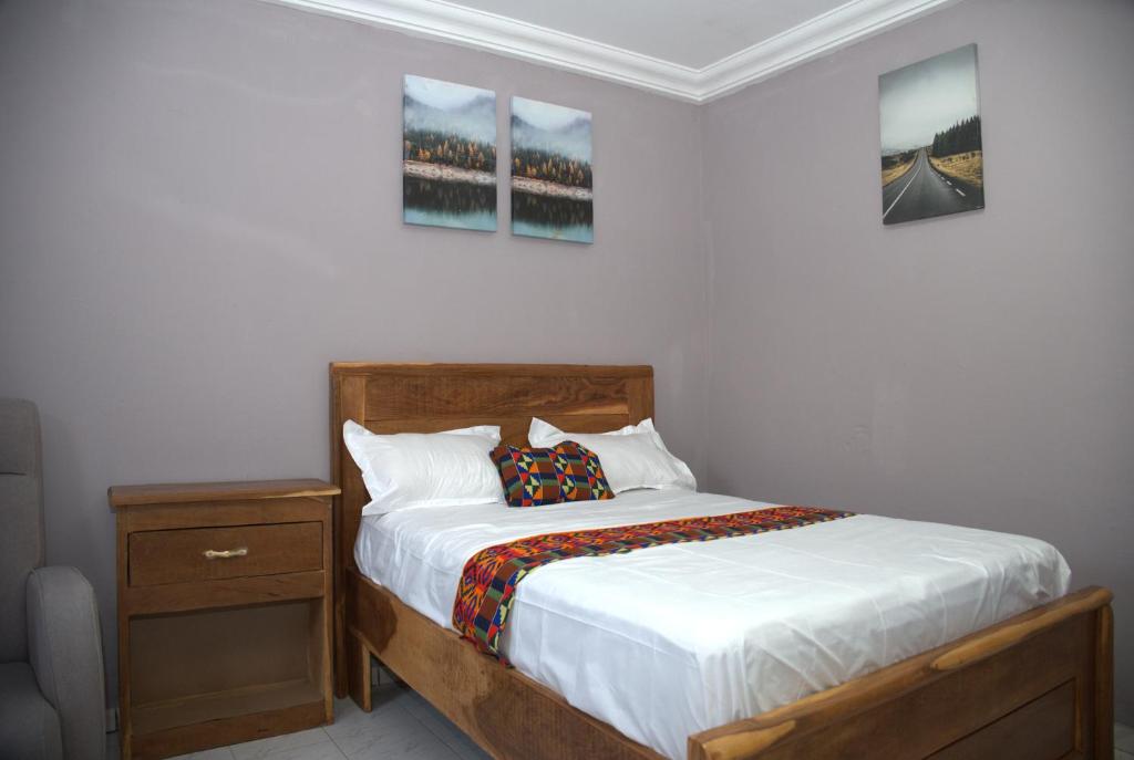 a bedroom with a bed and a nightstand and paintings on the wall at Faith and Grace Guest House in Lamin