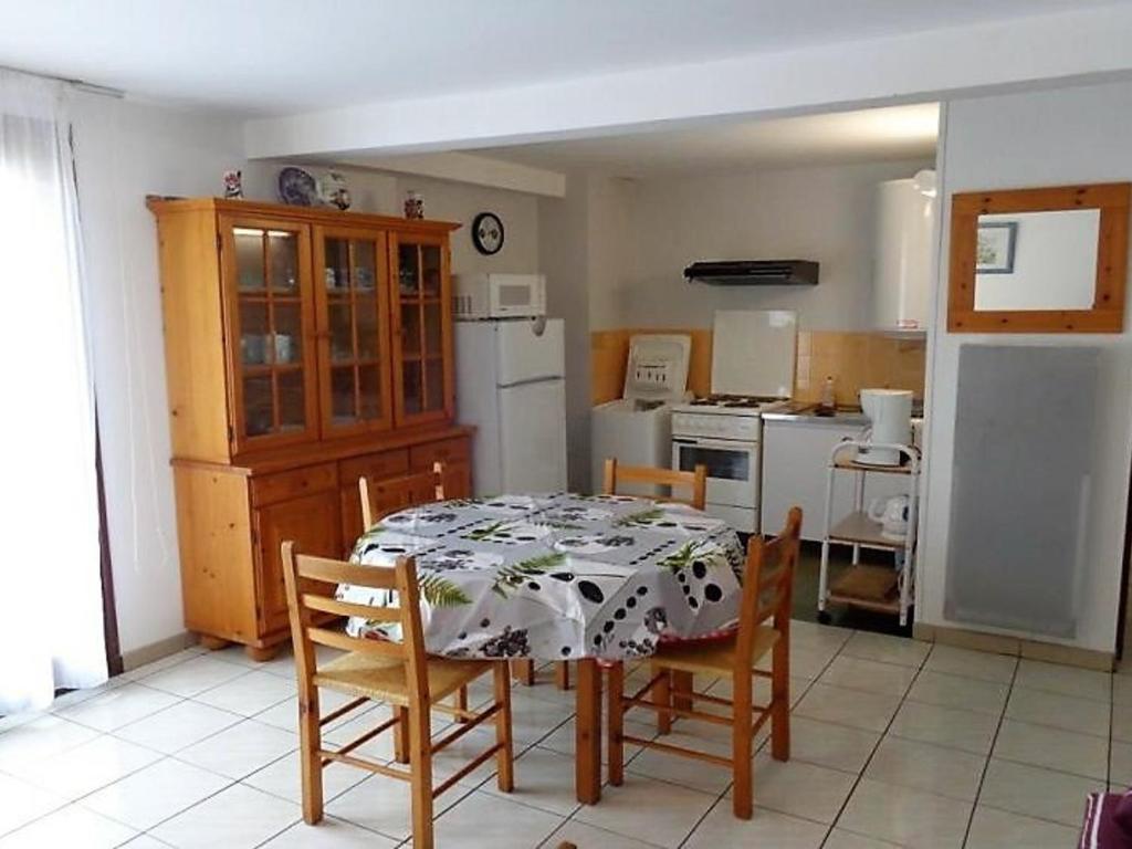une cuisine avec une table et des chaises et un réfrigérateur blanc dans l'établissement Appartement F2 avec balcon, 200m des cures, proche commerces, tout équipé, charges en sus - FR-1-703-76, à Amélie-les-Bains-Palalda