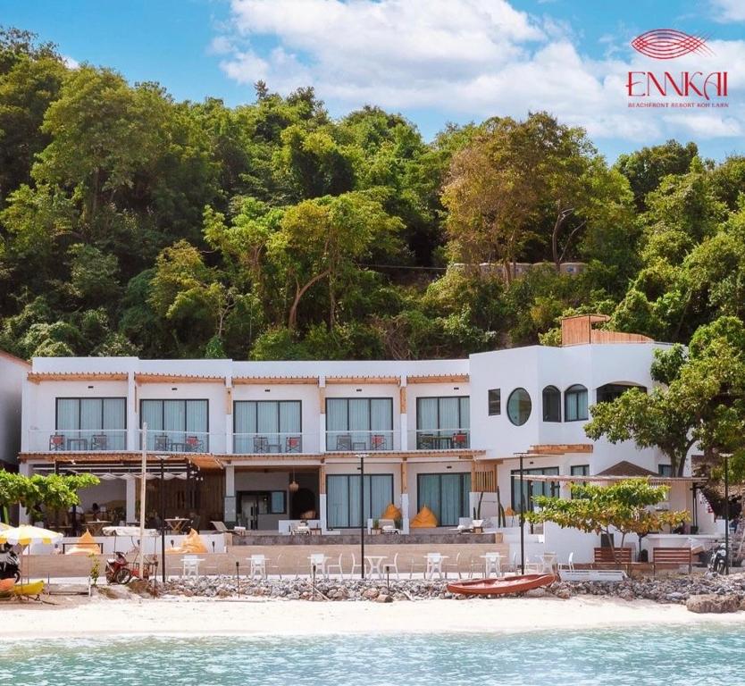 een groot wit gebouw aan het strand naast het water bij ENNKAI Beachfront Resort Koh Larn in Pattaya