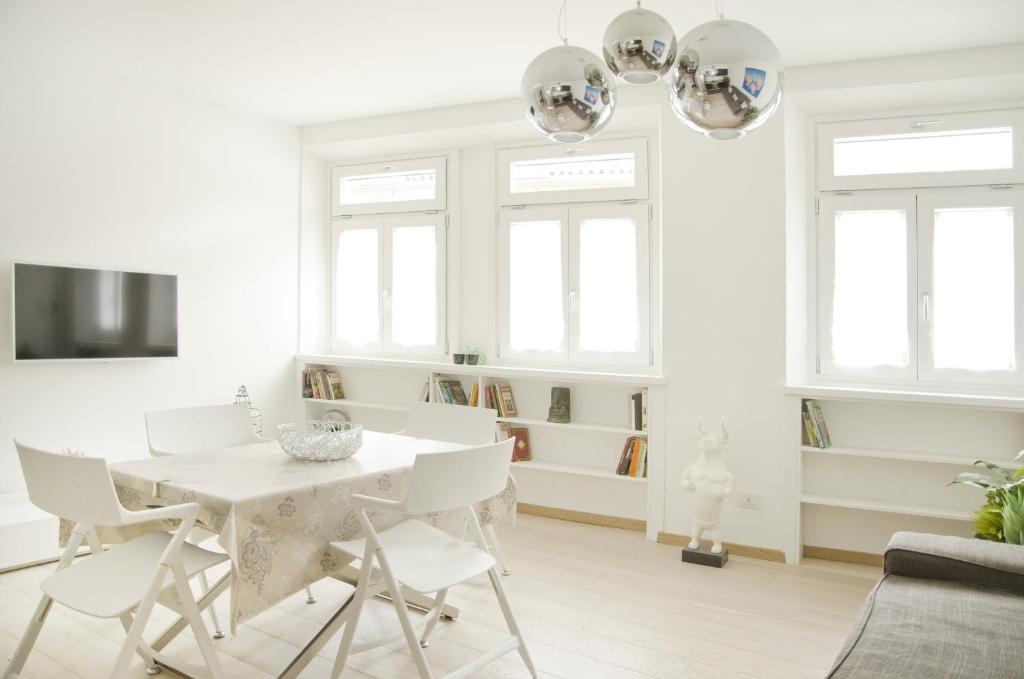 una sala de estar blanca con mesa blanca y sillas en Green Apartment en Bolzano