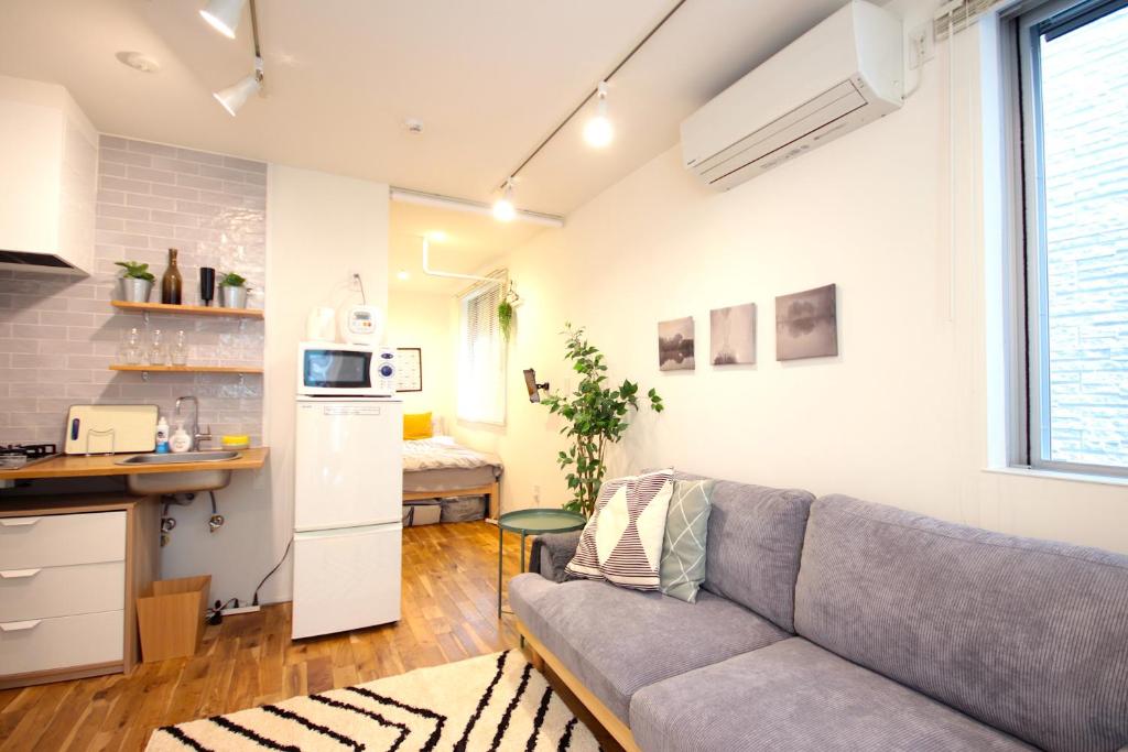 uma sala de estar com um sofá e uma cozinha em LaLaCUBE Kitasenju em Tóquio