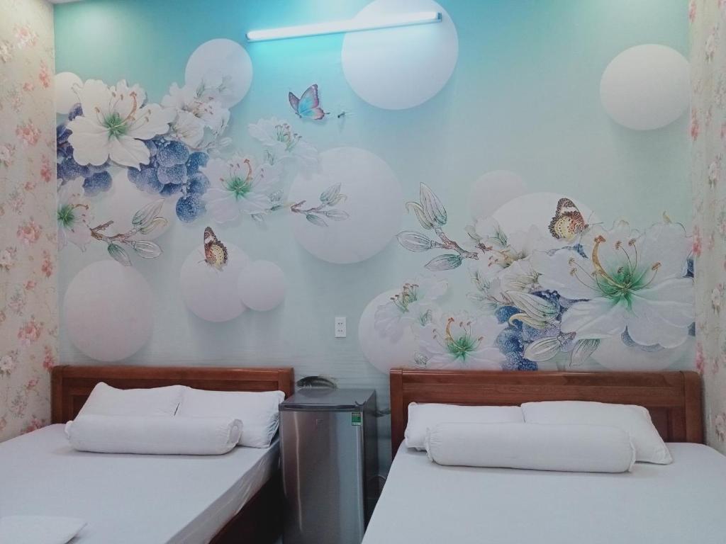 two beds in a room with flowers and butterflies on the wall at MOTEL MINH ANH in Ấp Rạch Mẹo