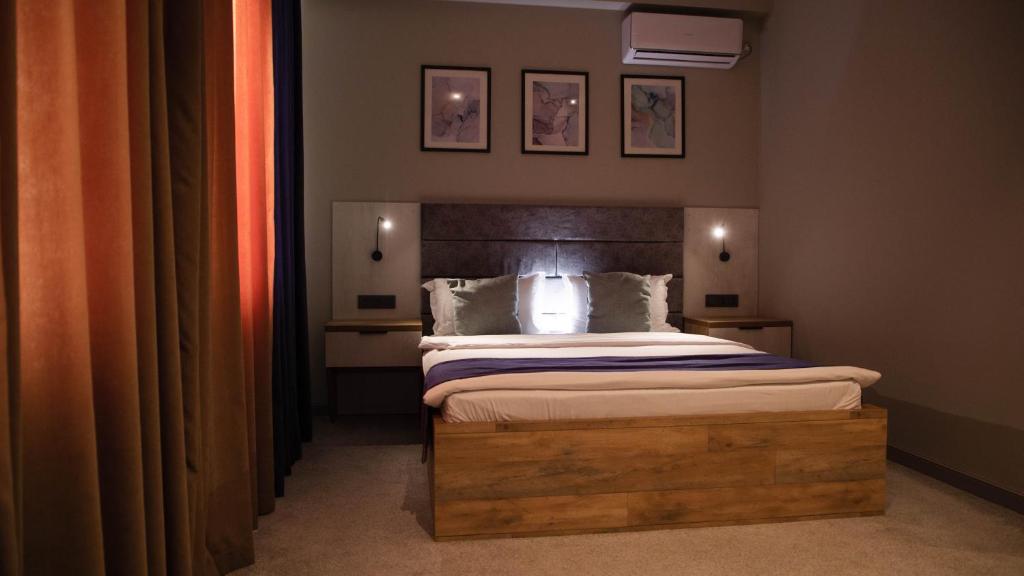 a bedroom with a large bed with a wooden headboard at Zodiac in Atyraū