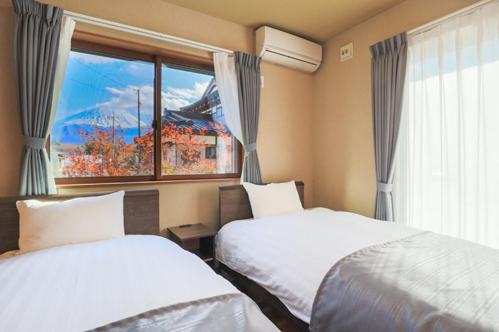 two beds in a room with a window at 24 ORIYA Mt Fuji -鳴沢 NARUSAWA- in Narusawa