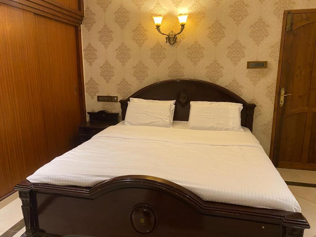 um quarto com uma cama grande e lençóis brancos em Queen's em Trivandrum