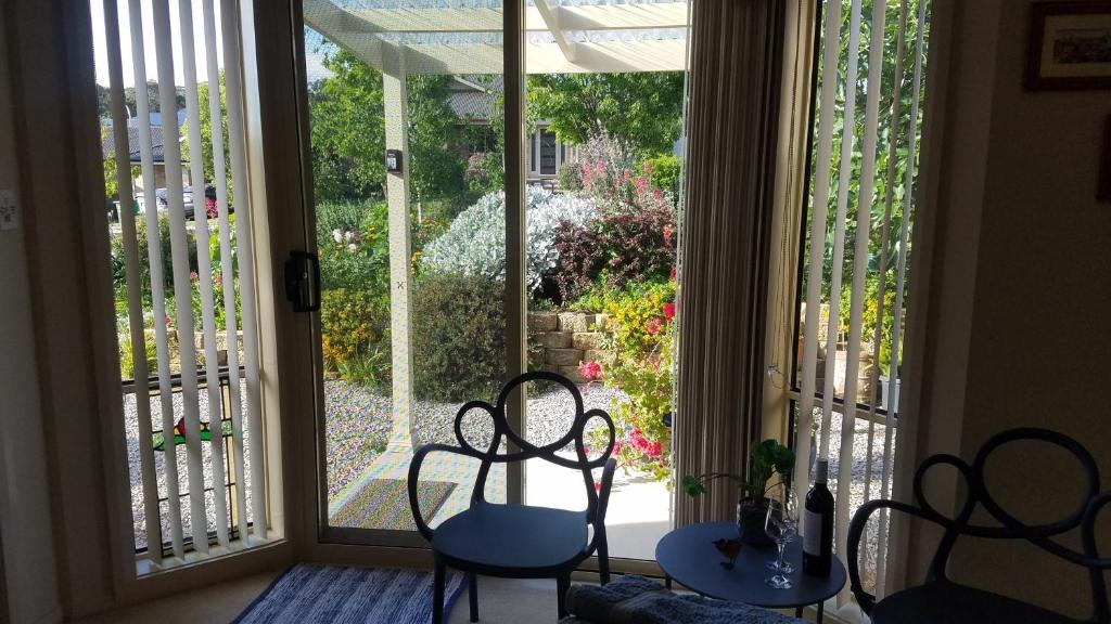 Habitación con una gran puerta corredera de cristal con mesas y sillas. en Blue Wren Retreat, en Orange