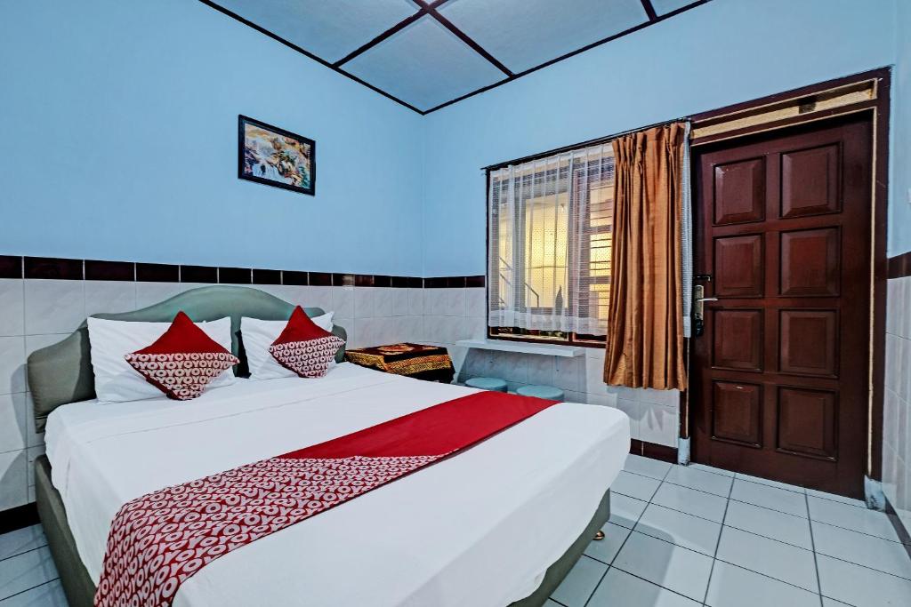 Un dormitorio con una cama con almohadas rojas. en OYO 92282 Hotel Muria, en Yogyakarta