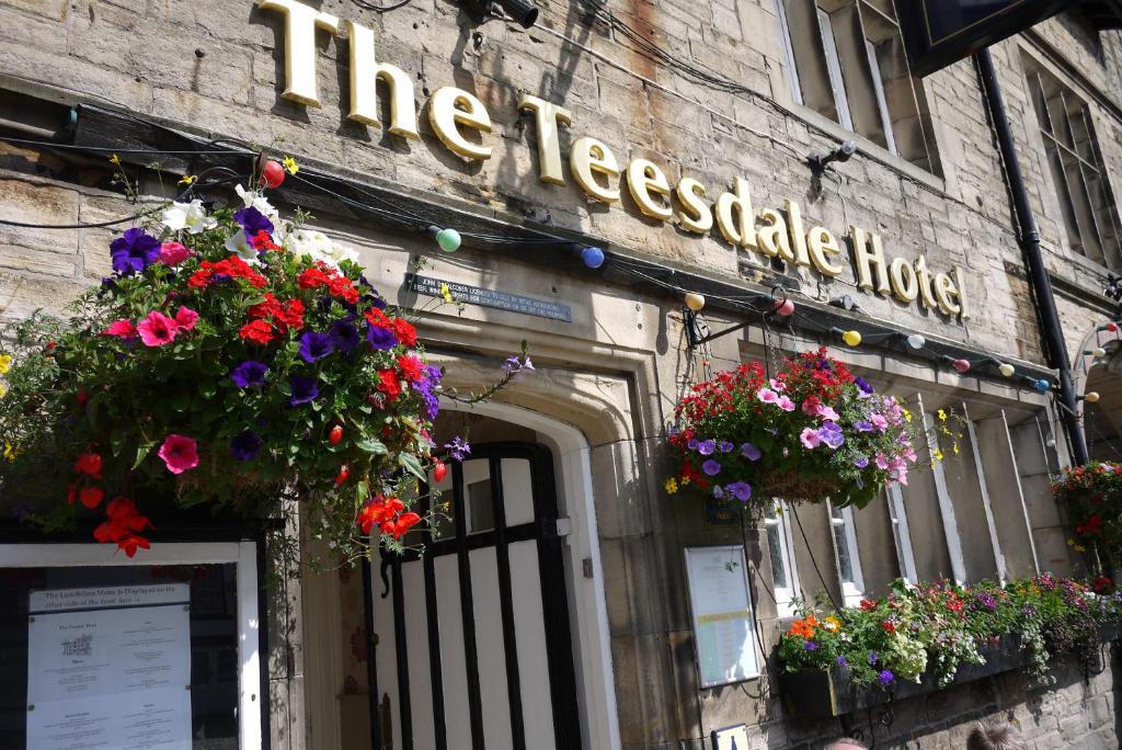 un edificio con cestini di fiori sulla parte anteriore di The Teesdale Hotel a Middleton-in-Teesdale