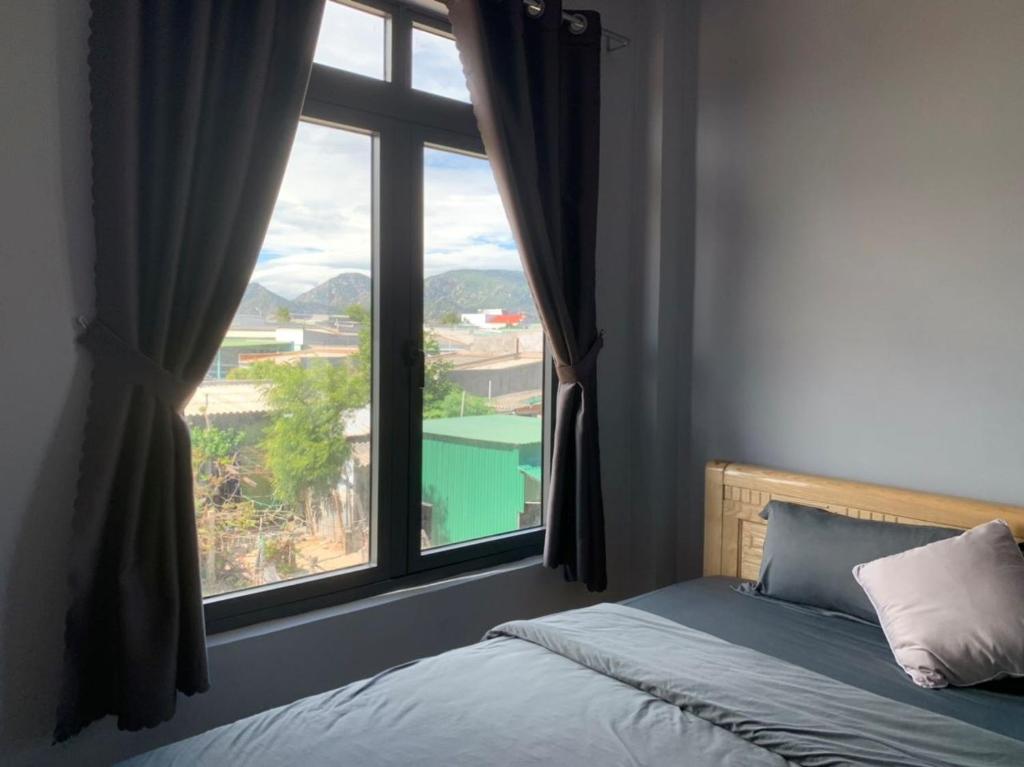 een slaapkamer met een bed en een groot raam bij Nomad Stay in Phan Rang