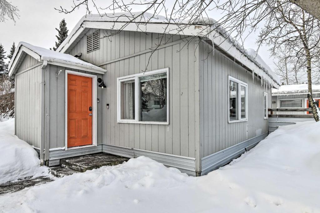 a gray house with a orange door in the snow at Anchorage Home, Minutes From Downtown! in Anchorage