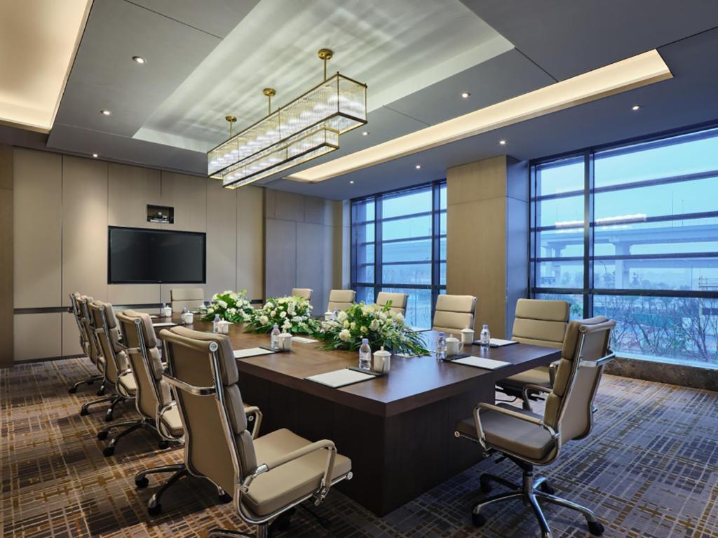 uma sala de conferências com uma grande mesa e cadeiras em The QUBE Hotel Ningbo North em Ningbo