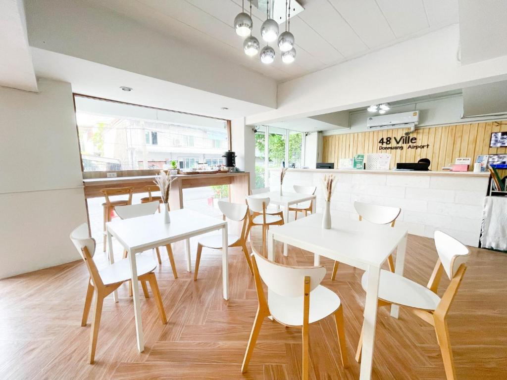 A bright hotel dining room with white tables and a reception counter.
