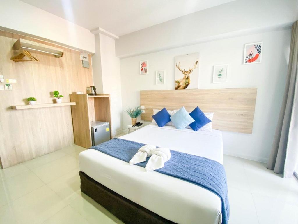 A bright double room with a large bed, blue accents and a compact refreshment area.