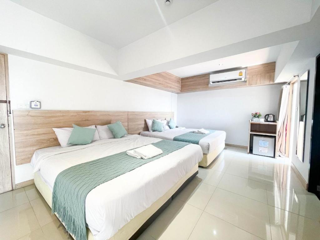 A spacious twin room with two dressed beds, wall-mounted air conditioning and a television.