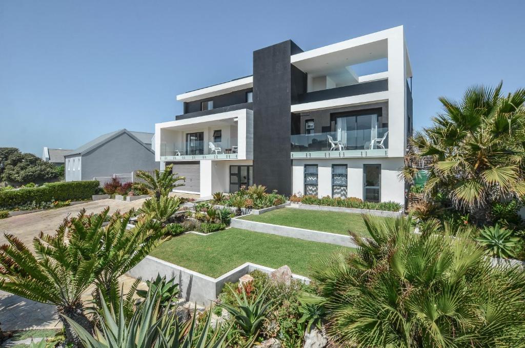 a large white house with palm trees in front of it at Orca House in Yzerfontein