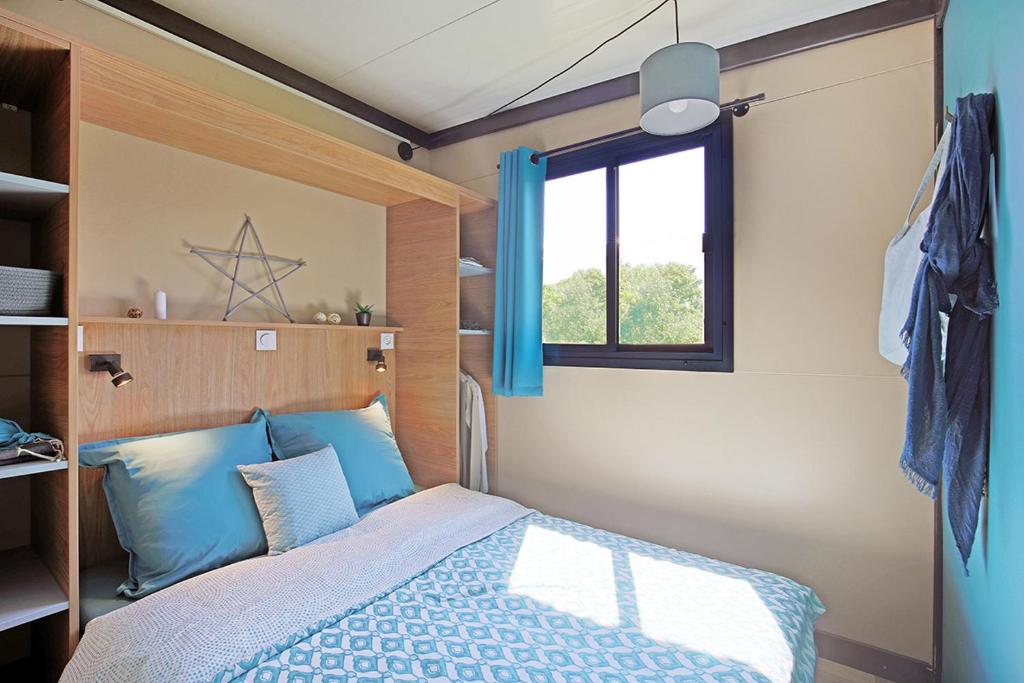 a bedroom with a bed with blue pillows and a window at RAS L'BOL in Olmeto