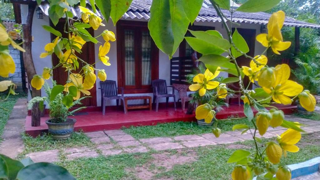a house with yellow flowers in front of it at Gangula Eco lodge in Sigiriya