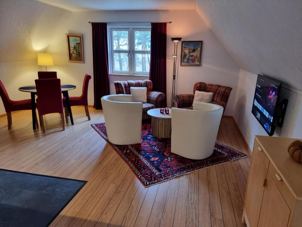 a living room with white chairs and a table at Linda Gård Apartments in Yngsjö
