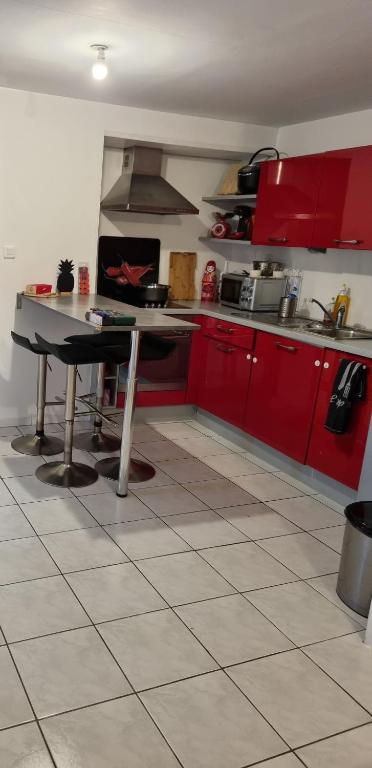une cuisine avec des armoires rouges et une table dans l'établissement Location saisonnière, à Agde