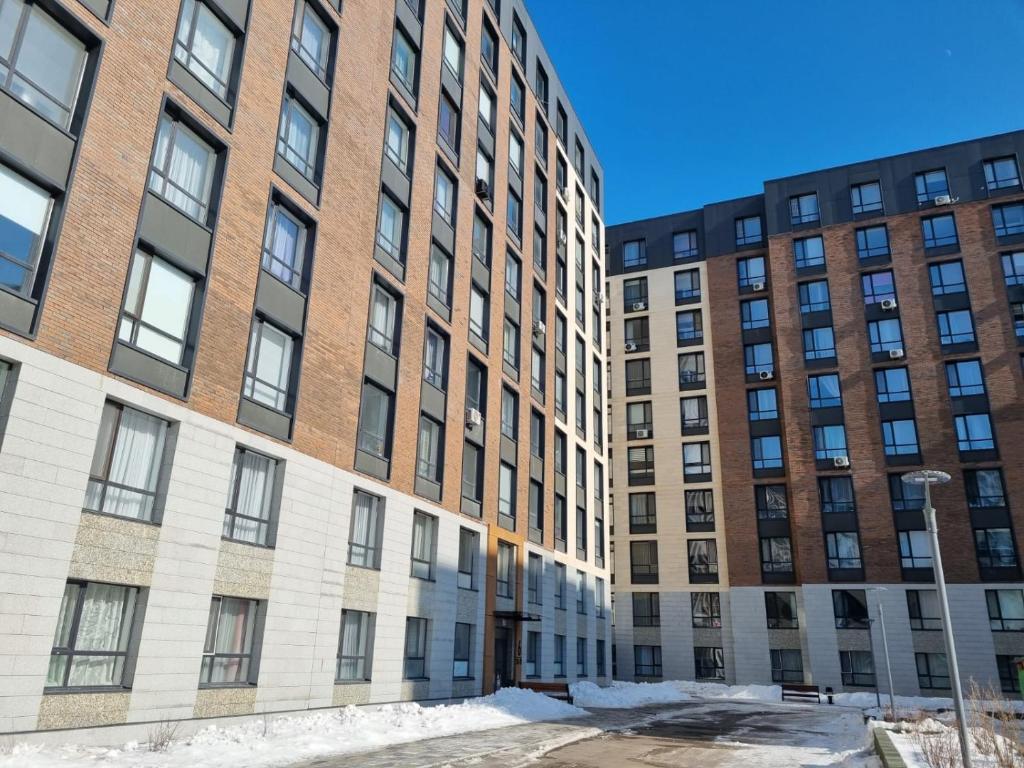 twee hoge gebouwen met sneeuw voor zich bij Квартира ЖК Apple city in Astana