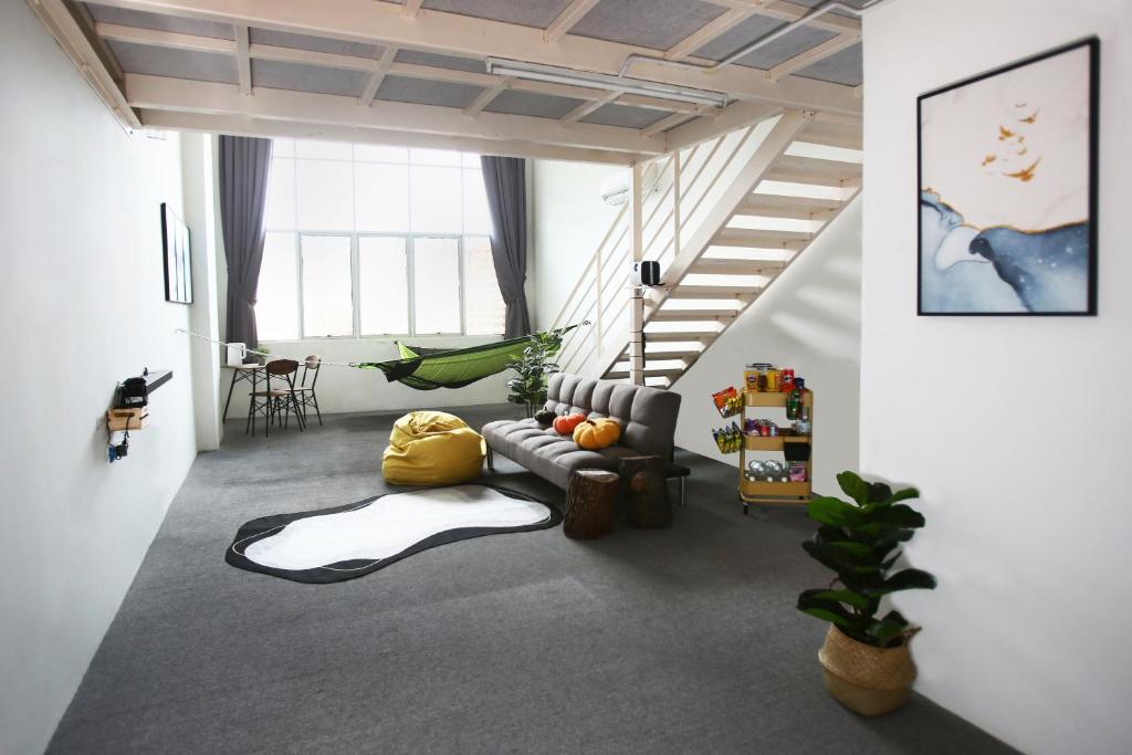 ein Wohnzimmer mit einem Sofa und einer Treppe in der Unterkunft Private 100 inches Screen Cinema at CEO Penang in Bayan Lepas
