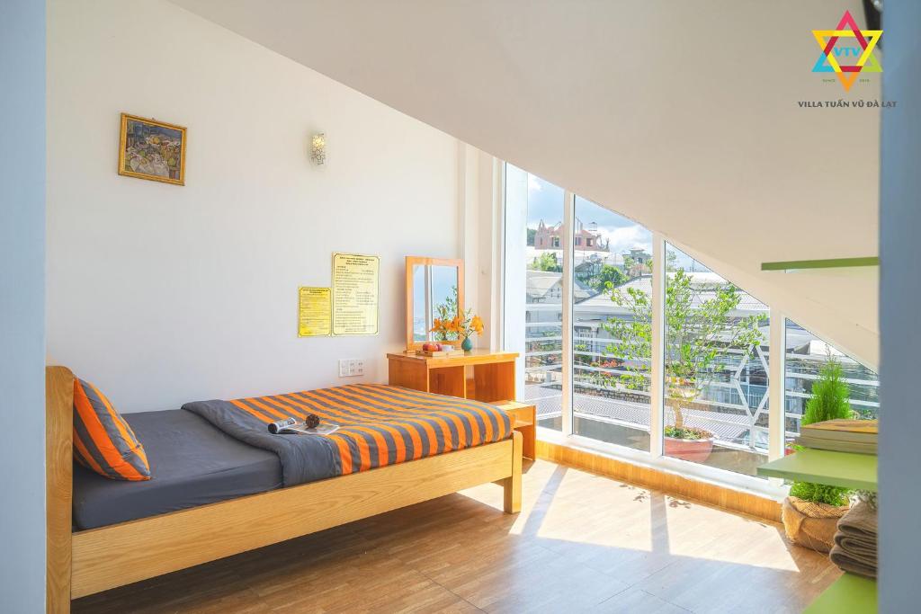 a bedroom with a bed and a large window at Villa Tuan Vu Da Lat in Da Lat