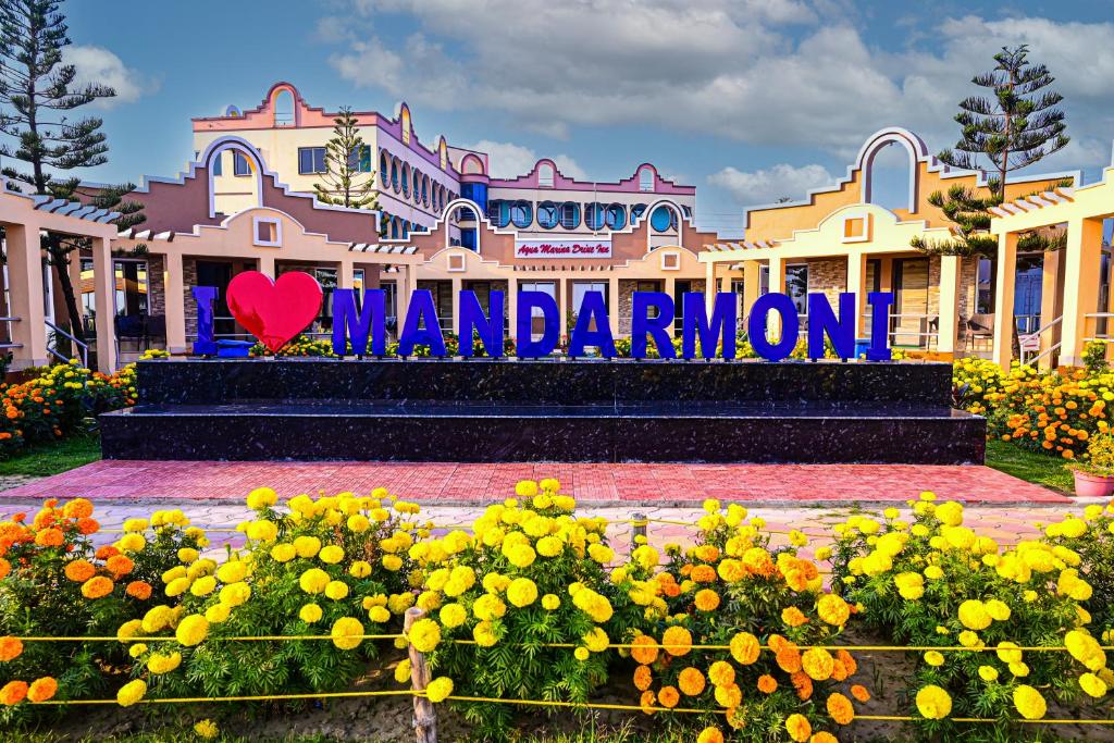 a sign in front of a building with flowers at Aqua Marina Drive Inn in Mandarmoni