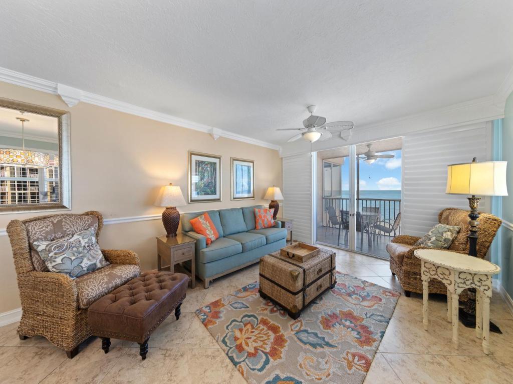 ein Wohnzimmer mit einem blauen Sofa und Stühlen in der Unterkunft Estero Island Beach Villas 706, 2 BR, Penthouse, Gulf Front, Pool, Sleeps 6 in Fort Myers Beach
