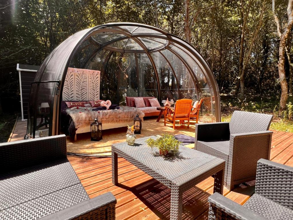 a gazebo with a couch and a table on a deck at Dôme S'féérique avec accès piscine in Saint-Évarzec