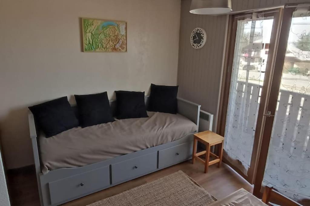 a bed in a living room with a window at Appartement T2 idéal pour une famille in Thollon