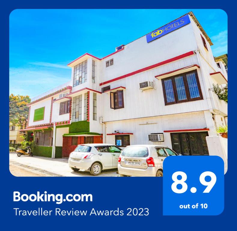a house with two cars parked in front of it at FabHotel Limewood in Dehradun