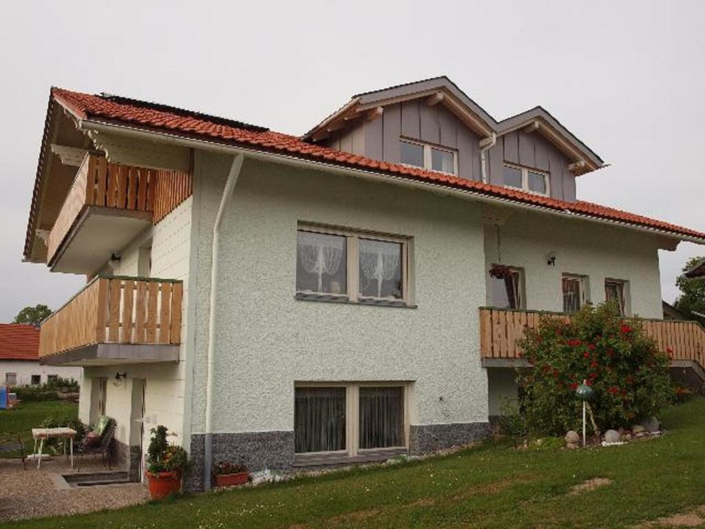 a white house with wooden balconies and a yard at Ferienwohnung Christa in Mauth