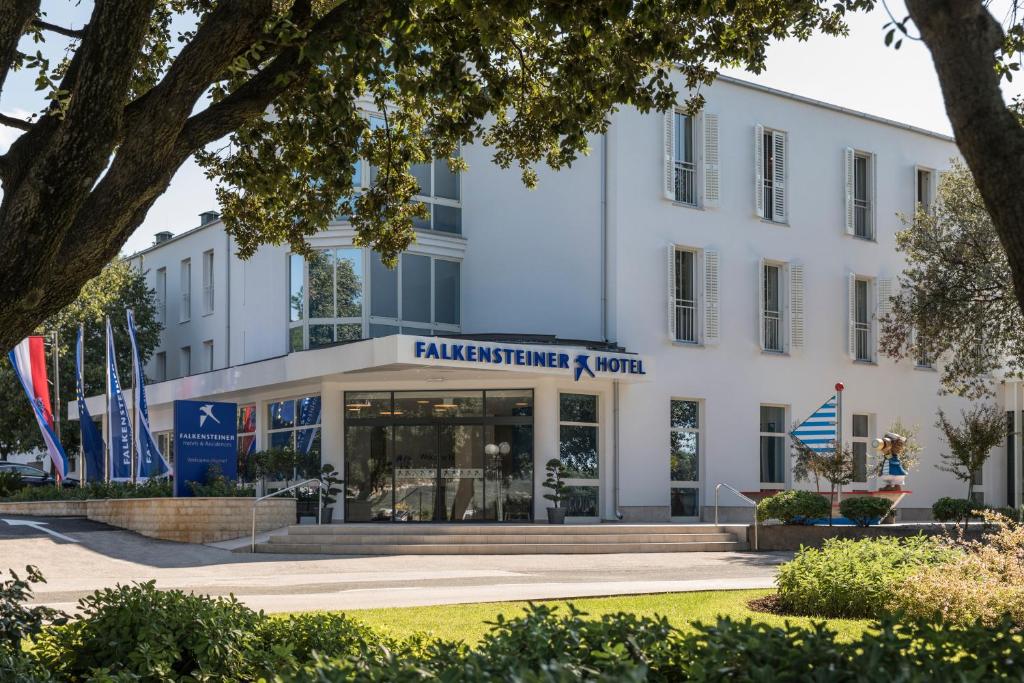a white building with a sign on it at Falkensteiner Hotel Park Punat in Punat