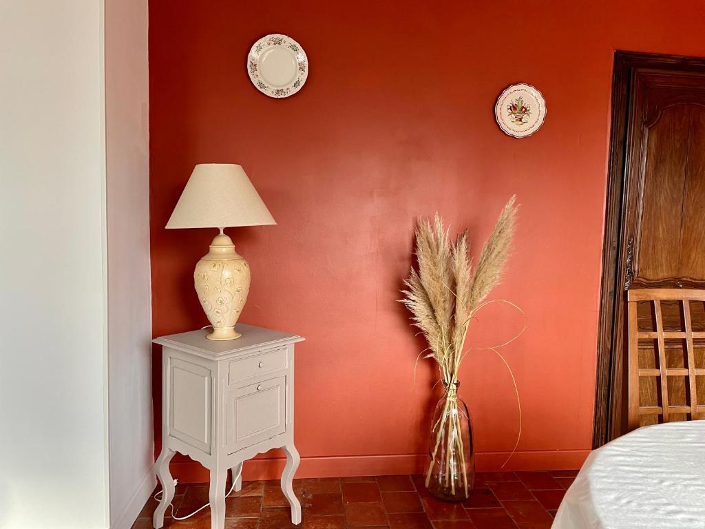 una camera da letto con pareti arancioni e un tavolo con una lampada di La Renaissance a Bayeux