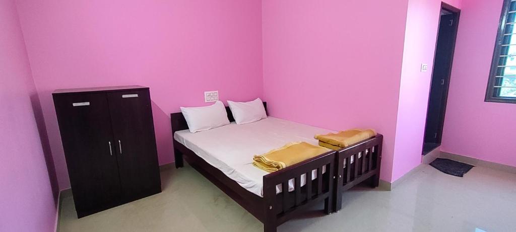 ein kleines Schlafzimmer mit einem Bett und einer rosa Wand in der Unterkunft STAYMAKER Madhu Residency in Sāgar